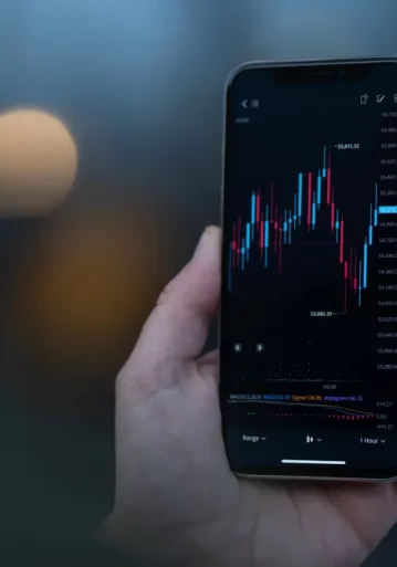 trader-looking-at-mobile-phone-with-stock-chart-on-2023-11-27-05-23-24-utc